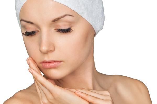 A woman in a spa headband gently touching her face, showcasing radiant skin and relaxation.
