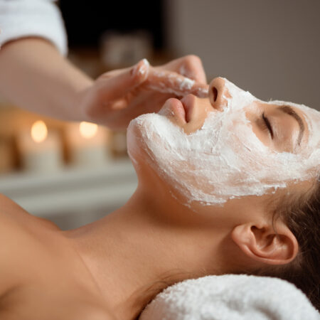 A woman receives a relaxing facial treatment in a tranquil spa environment.