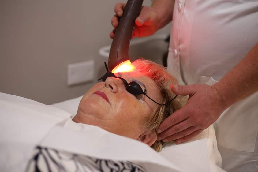 Person undergoing red light facial therapy while wearing protective goggles.