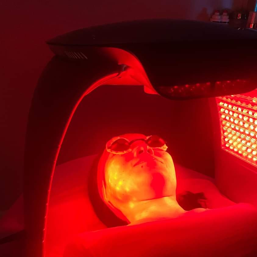 Person undergoing red light therapy session in a wellness clinic.