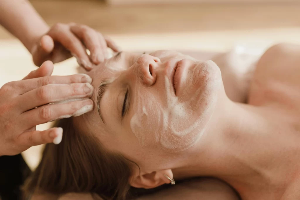 Woman enjoying a facial treatment with gentle cleansing by a professional at a spa.